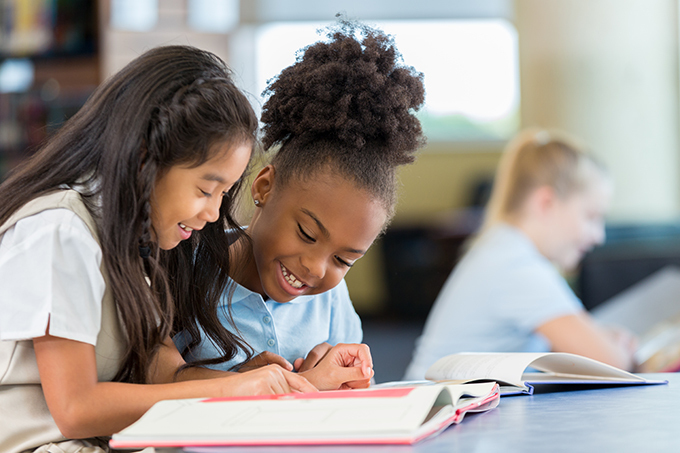 Two girls engaging in reading.