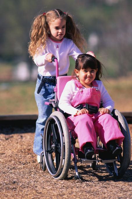 girl pushing friend in wheelchair girl pushing friend in wheelchair